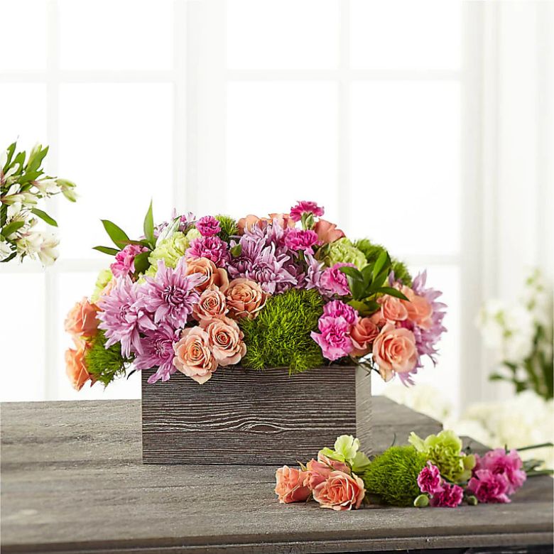 bouquet of peach spray roses, green button pompon, pink mini carnations and lavender cushion pompons