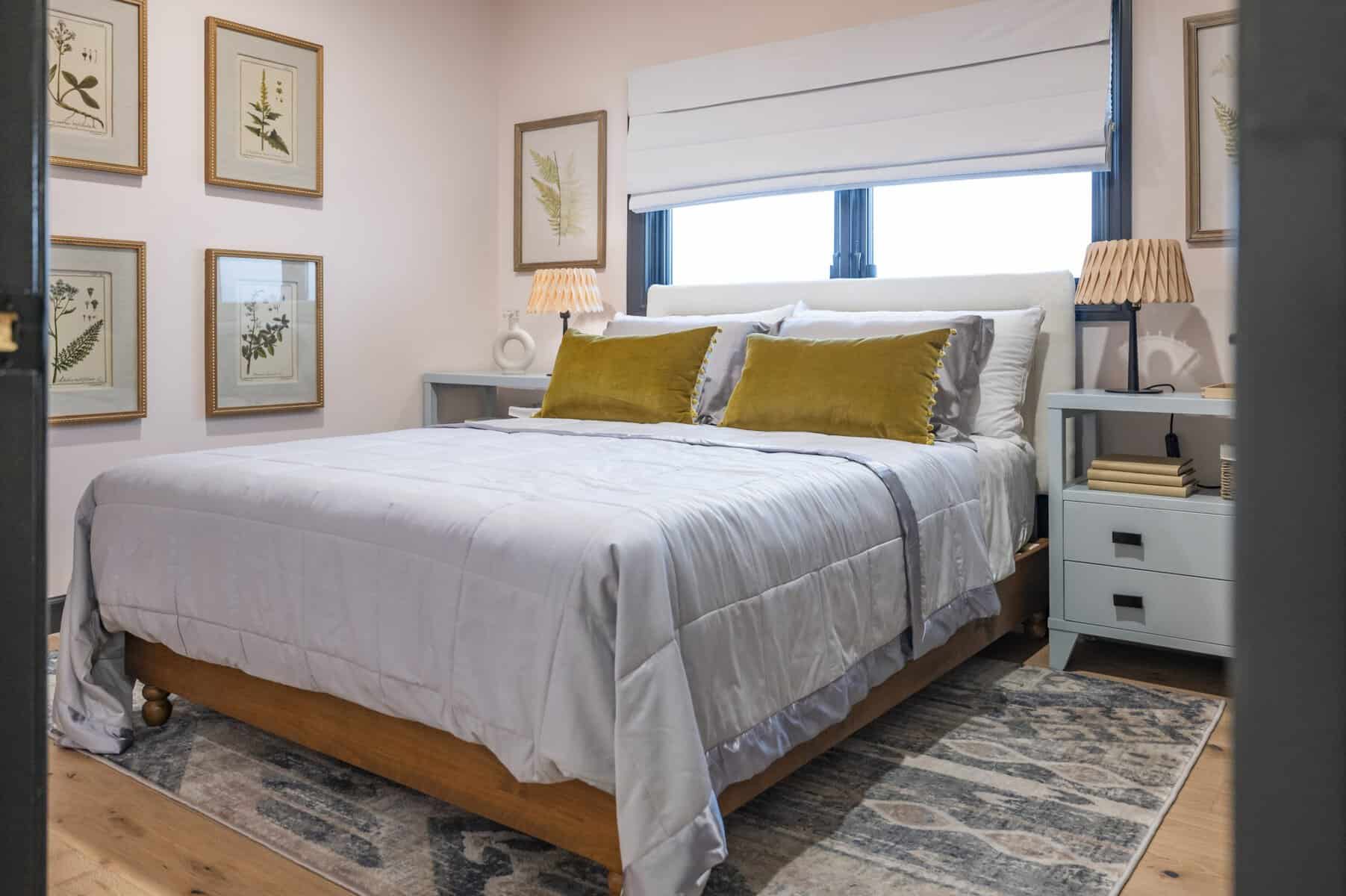Cozy bedroom with white bedding, yellow pillows, and botanical wall art