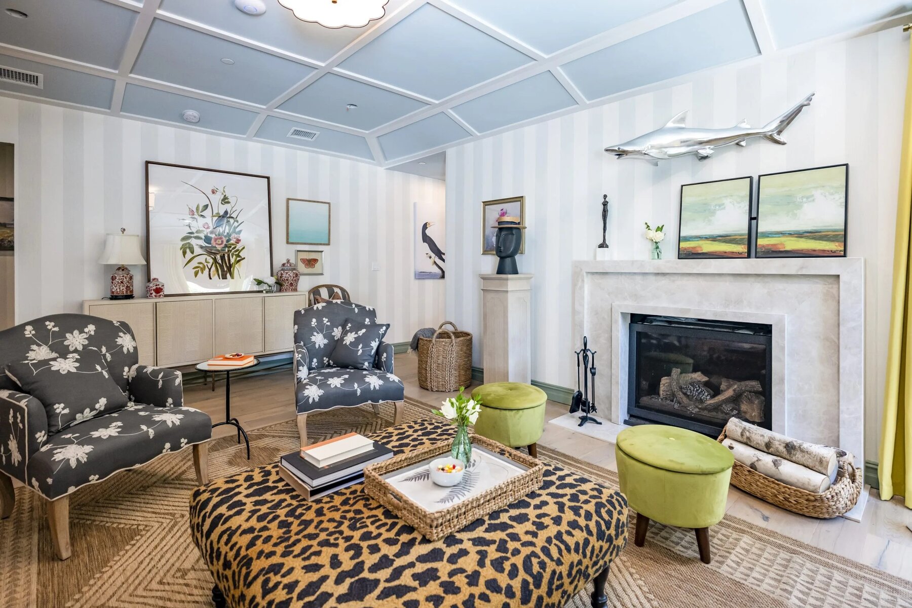 Eclectic room with patterned chairs, green ottomans, and a fireplace under a shark sculpture