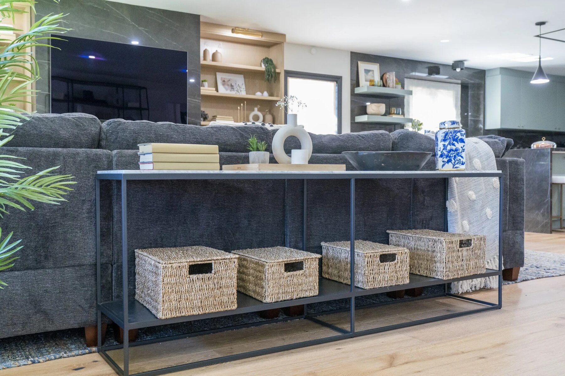 Modern living room with dark gray sofa, console table with woven storage baskets, and decorative accents