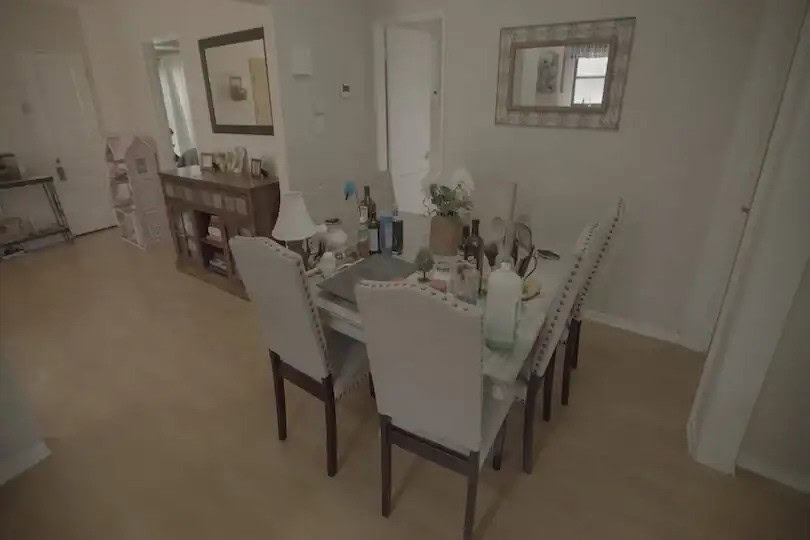 Dining room with light wood floors, upholstered chairs, cluttered table, and wall mirror
