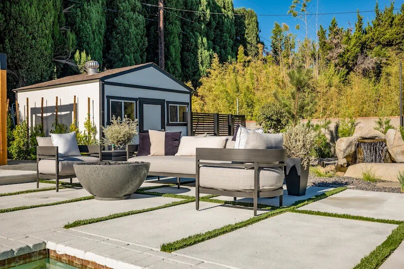 Modern patio with neutral seating, fire pit, and waterfall feature