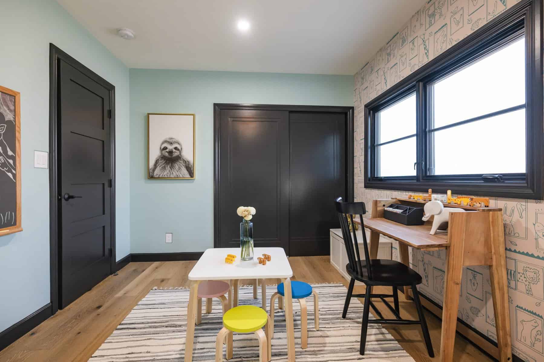 Kids’ playroom with striped rug, small table, and wooden desk