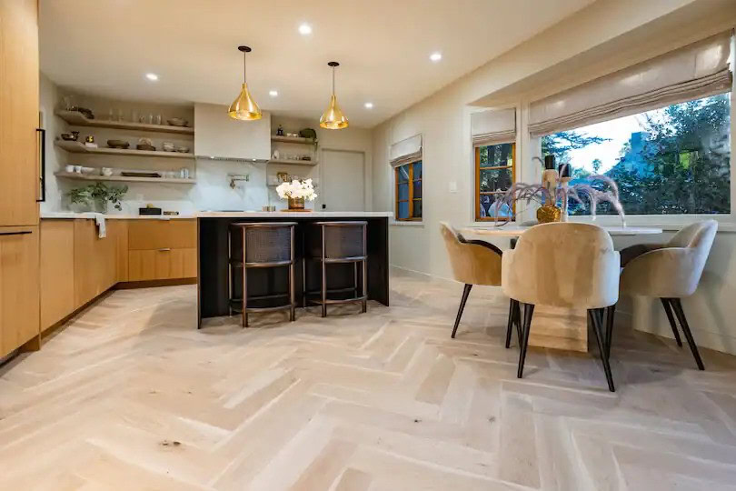 Kitchen with herringbone floors, gold lights, open shelves, and dining area