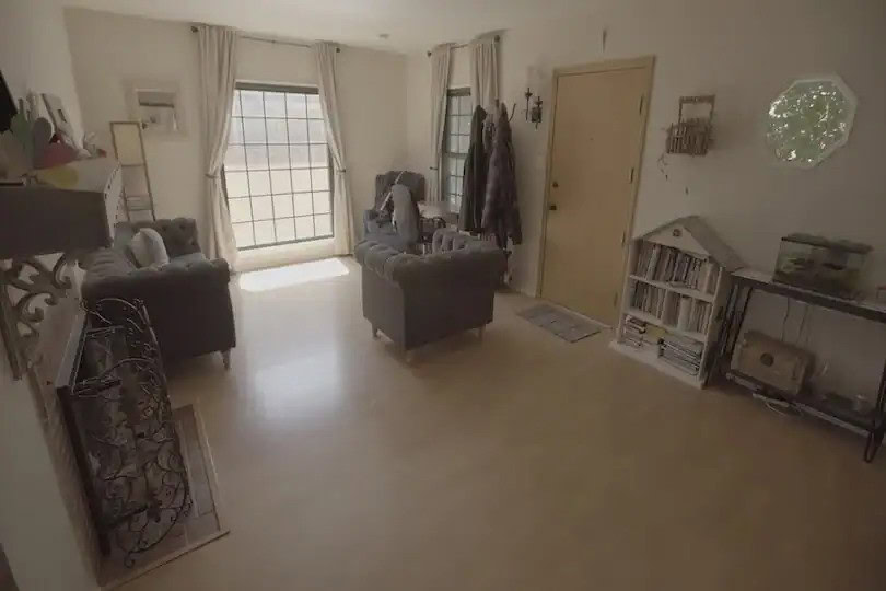 Cozy living room with tufted chairs, light wood floors, and large front windows