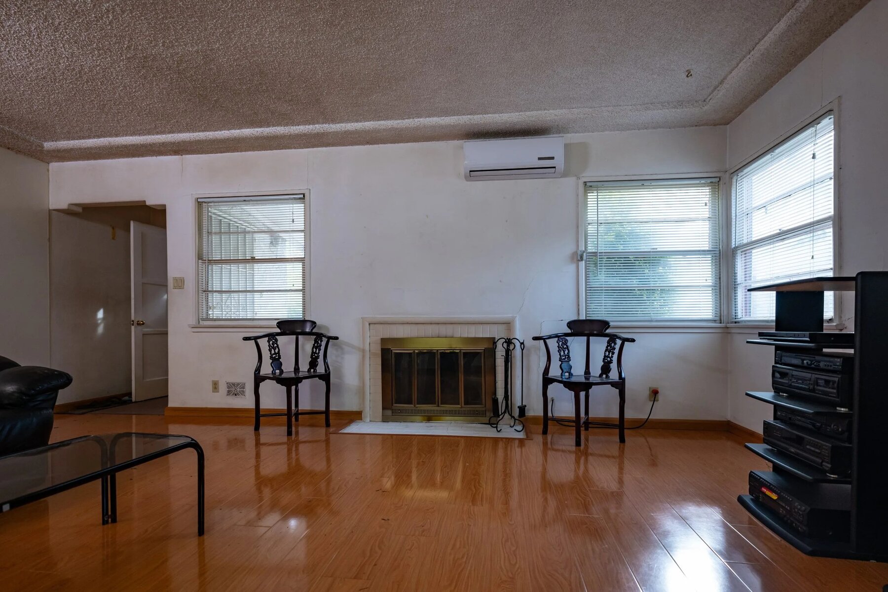 Empty living room with two chairs, a fireplace, and a television stand