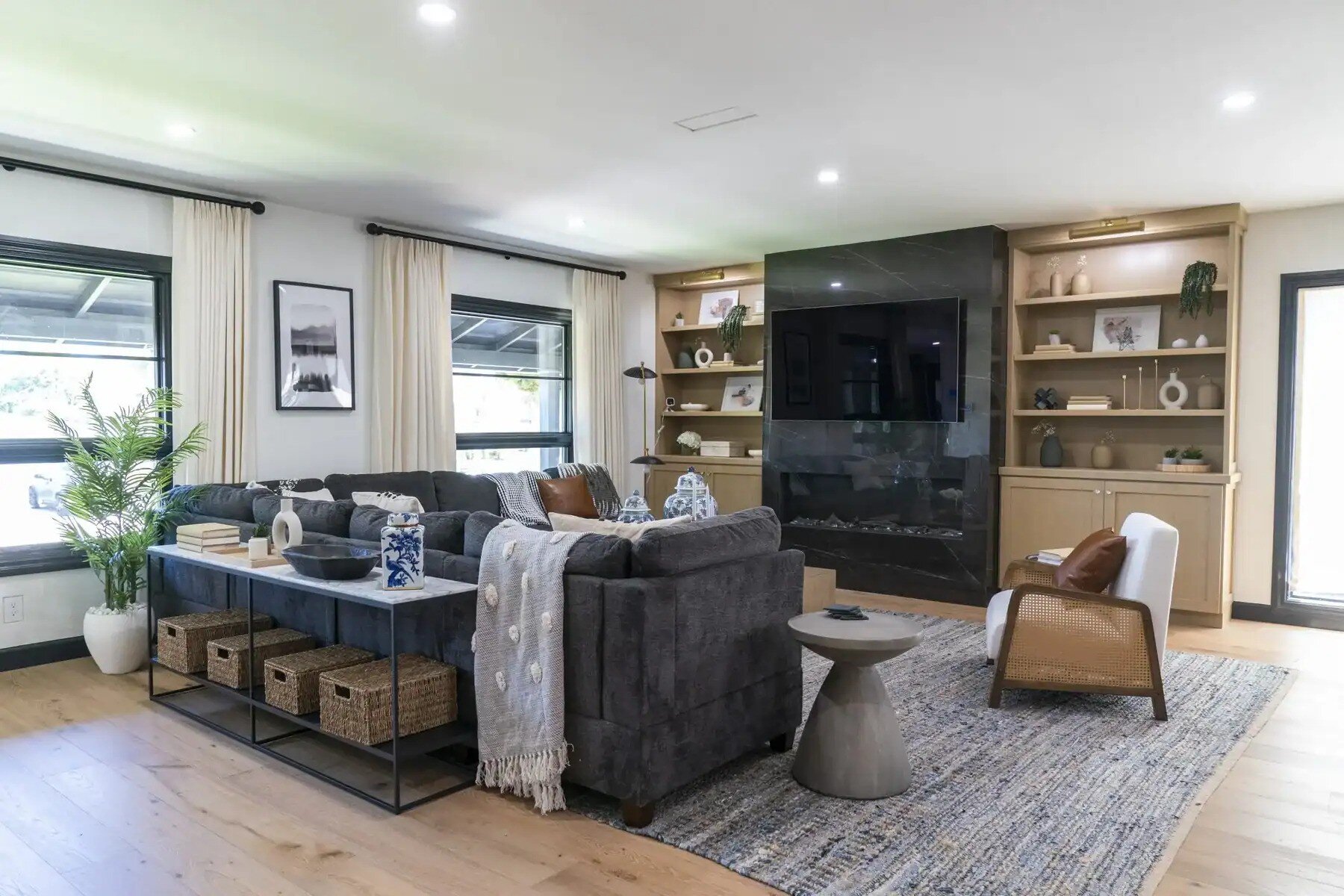 Cozy living room with gray sectional, built-ins, and black fireplace wall