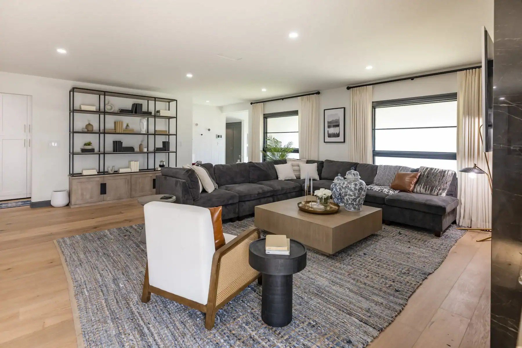 Spacious living room with a large gray sectional, modern shelving, and a blue patterned rug