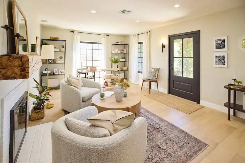 Cozy living room with neutral furniture, a round coffee table, a fireplace, and large windows