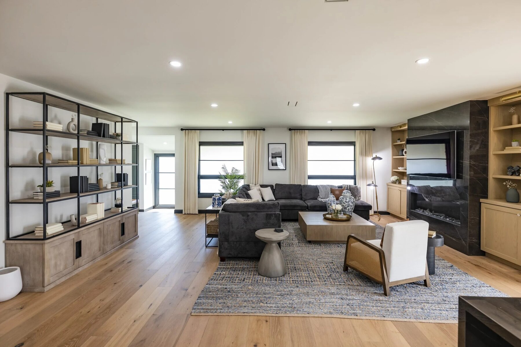 Spacious living room with large sectional sofa, open shelving, and built-in fireplace
