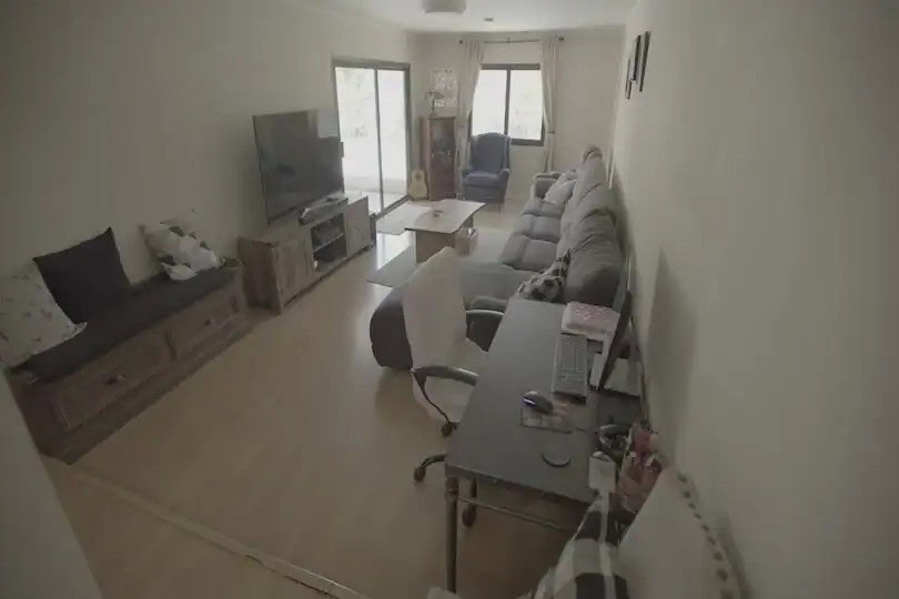 Living room with a sectional sofa, TV, desk setup, and natural light from large windows