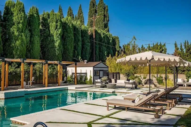 Modern poolside with lounge chairs, shaded seating area, and pergola