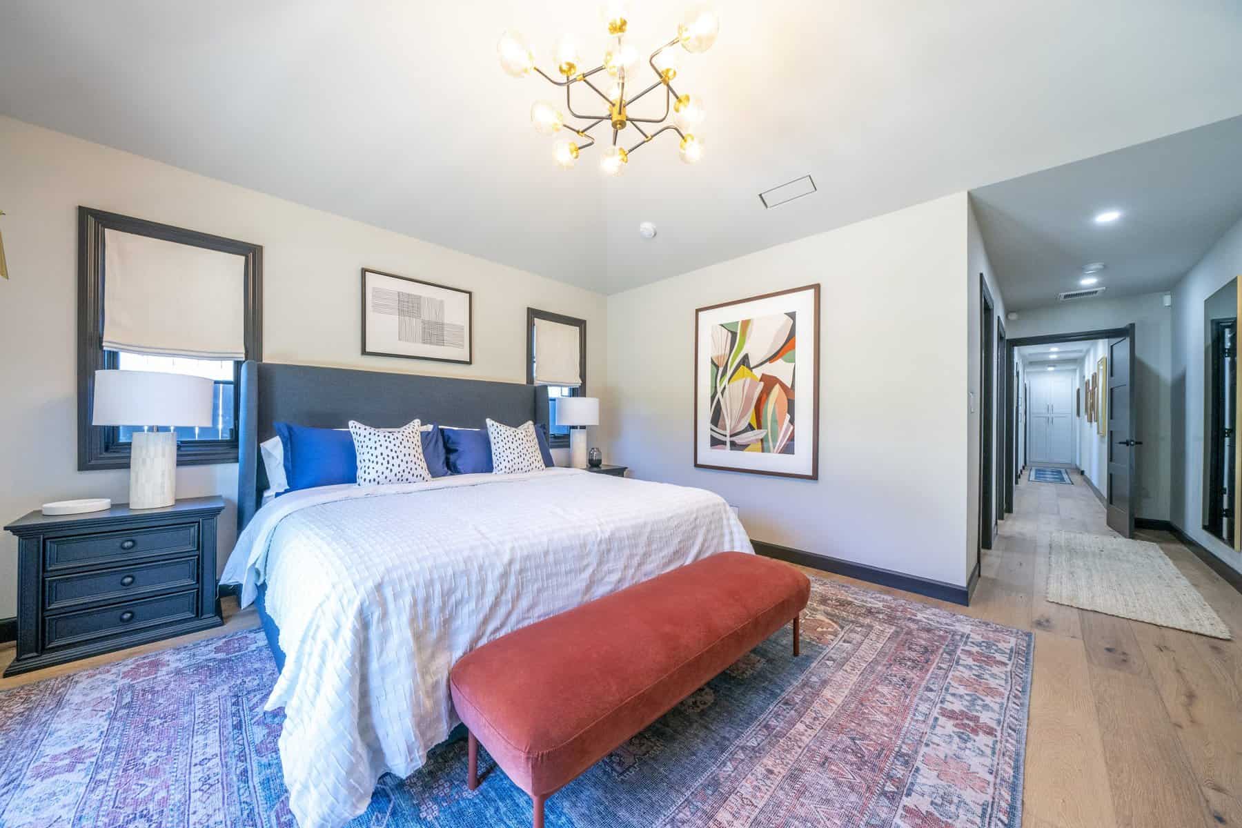 Spacious bedroom with a large bed, colorful bench, modern decor, and hallway view