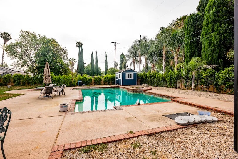 Backyard with a swimming pool, patio furniture, and lush greenery