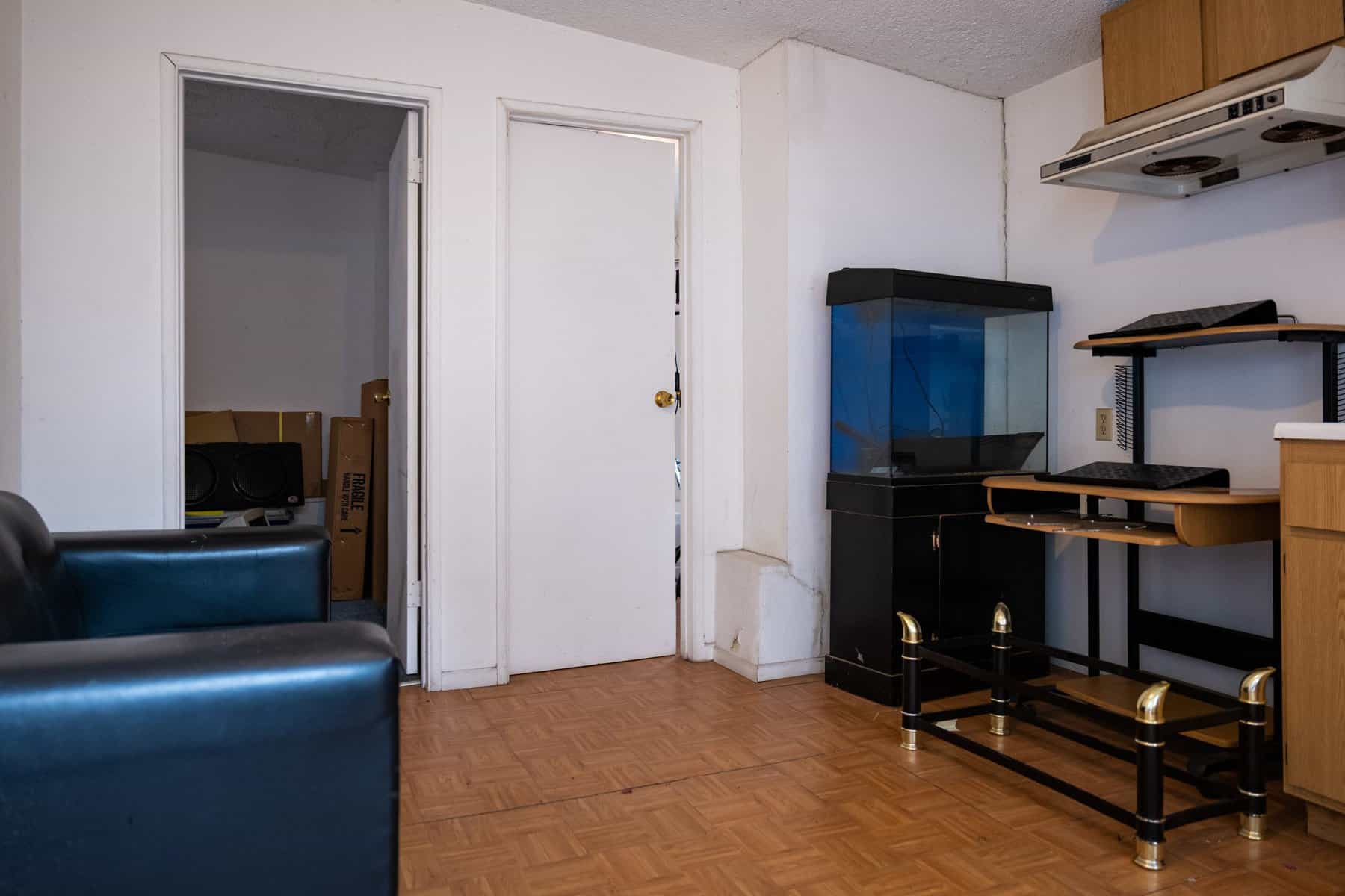 Empty room with a black fish tank, desk, and a door leading to another space