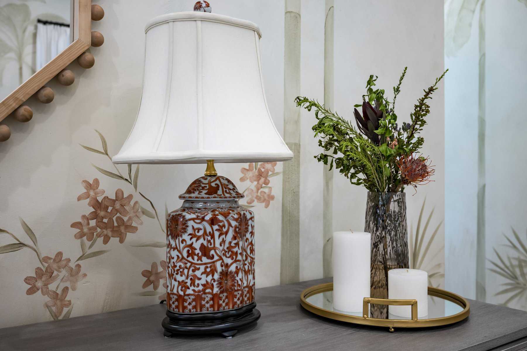 Table with ceramic lamp, floral vase, and candles on a tray