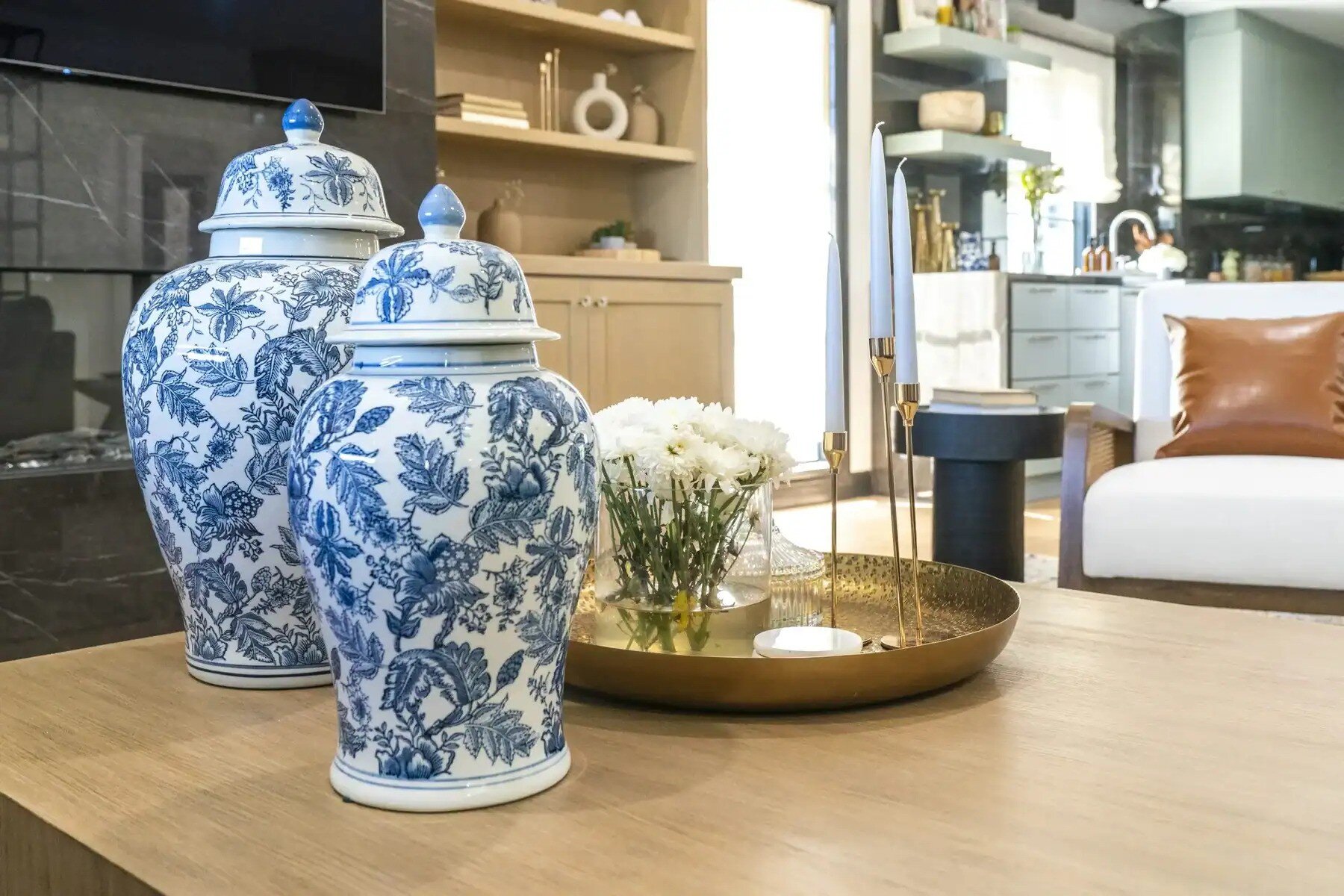 Elegant living room with blue and white porcelain jars, gold tray decor, and modern furnishings