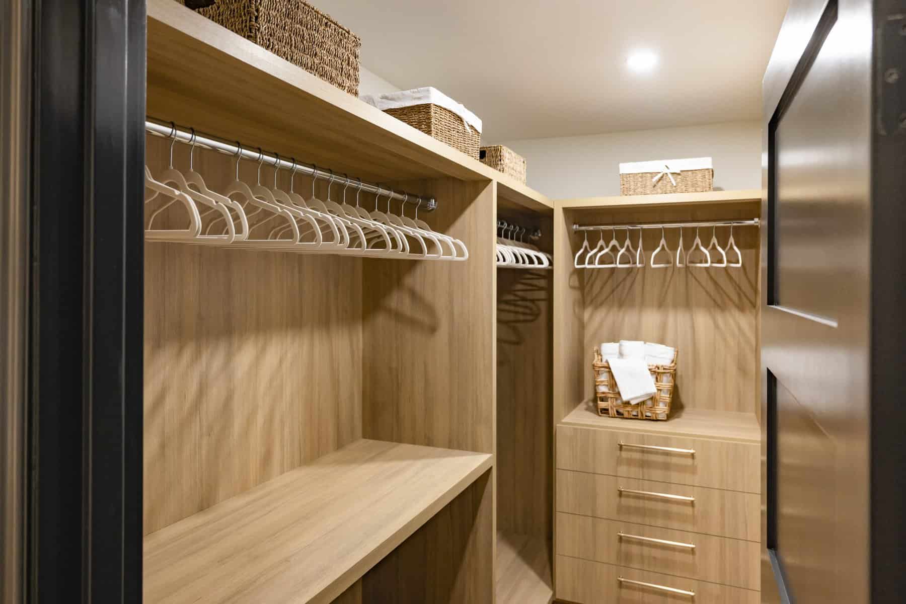Walk-in closet with wooden shelving, hanging rods, and baskets, along with a set of drawers