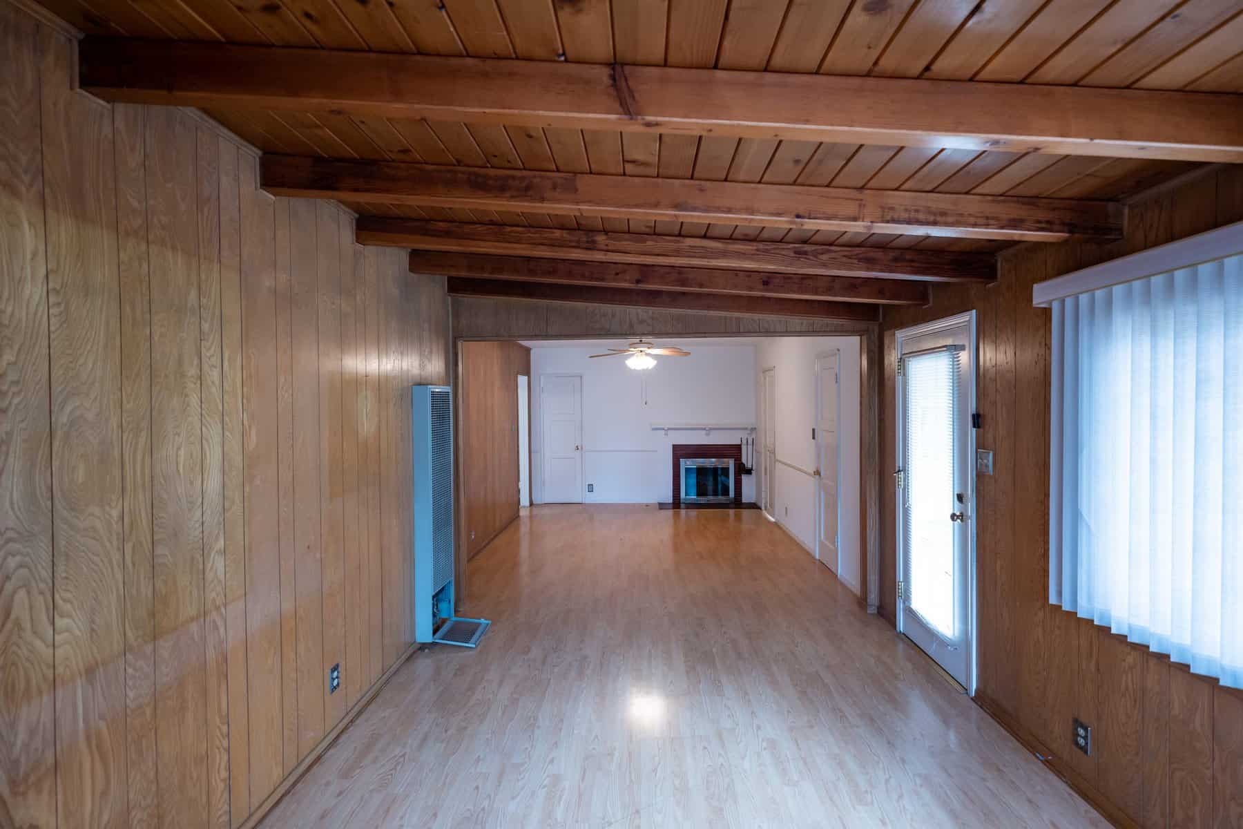 Living room with wood paneling, wood ceiling, fireplace, windows, and sliding glass door