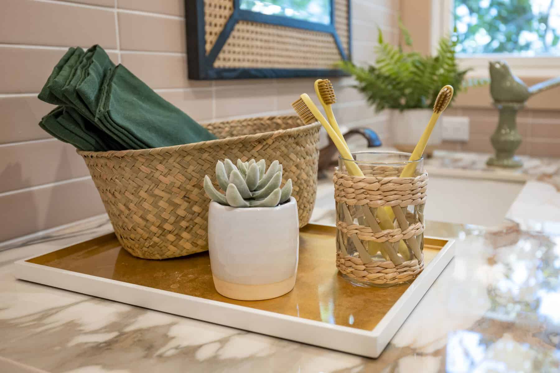 Bathroom counter with woven basket, succulent, and toothbrushes in a wicker-wrapped glass