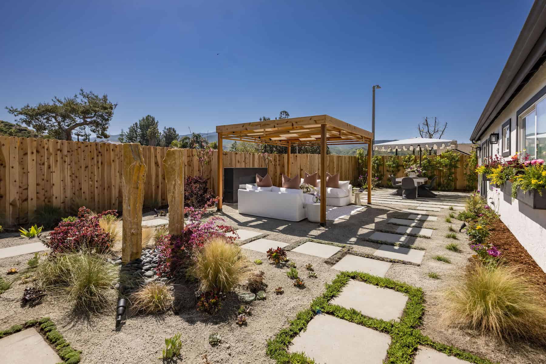 Modern backyard with pergola seating, drought-tolerant landscaping, and stone pathway