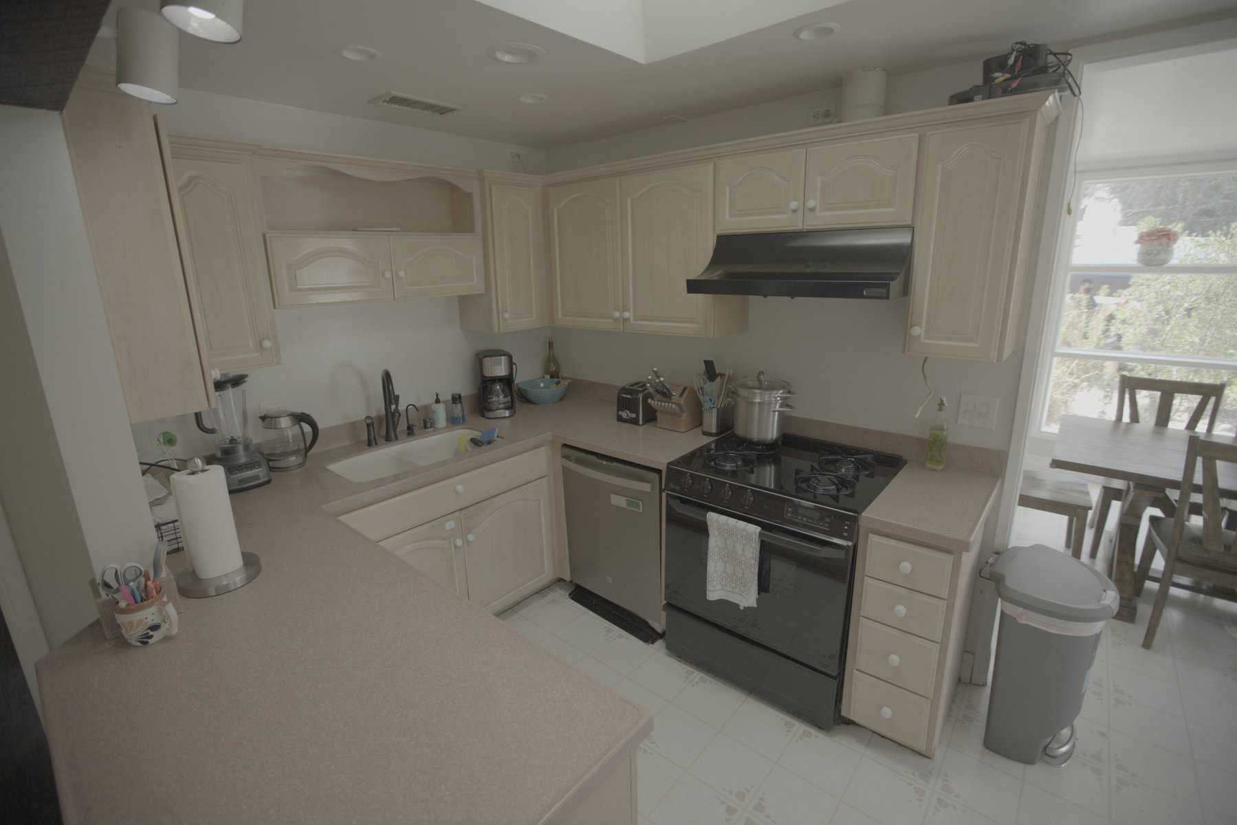 Traditional kitchen with beige cabinets, black appliances, and a cozy dining area by the window