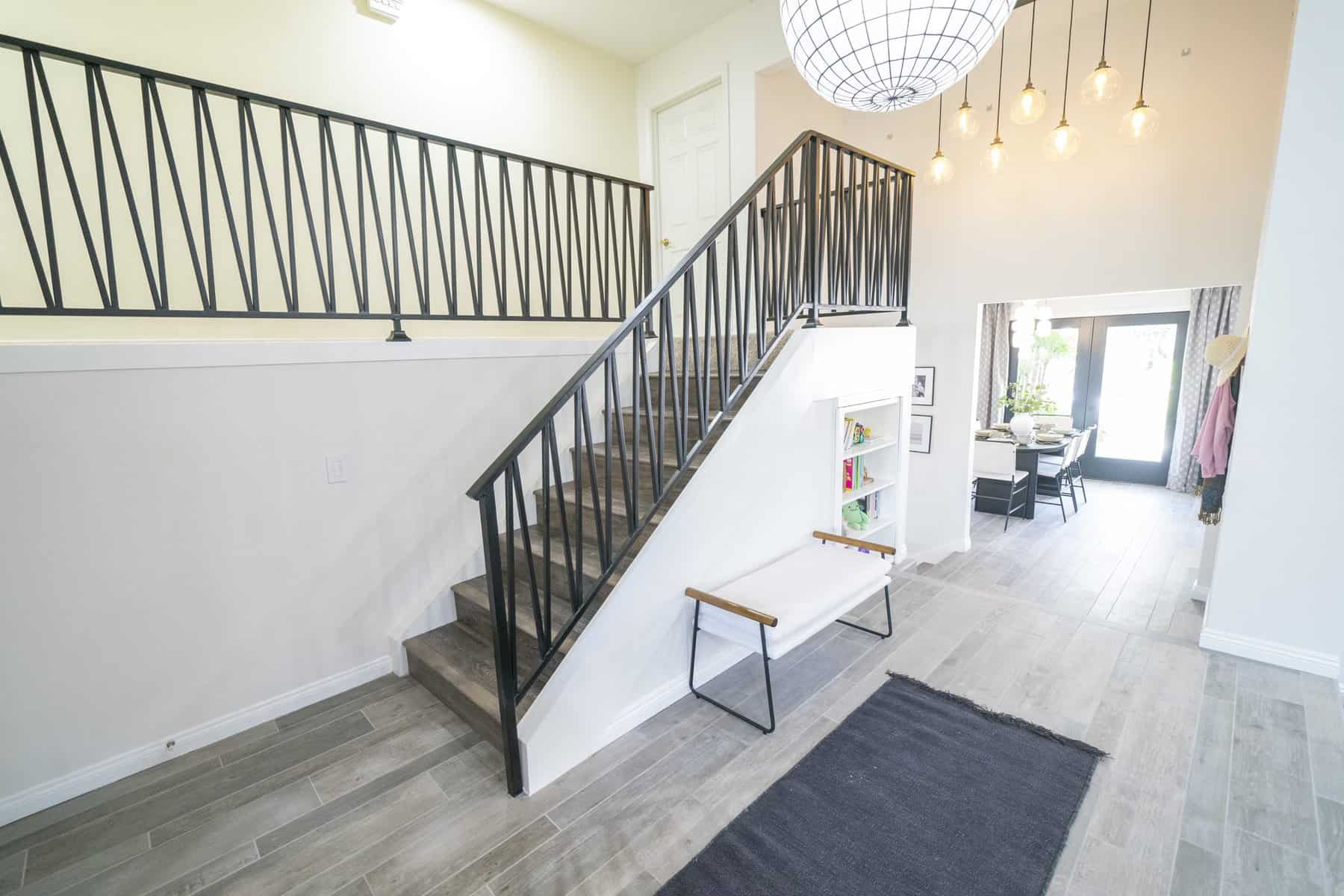 Modern entryway with a black metal staircase, pendant lighting, and open dining area
