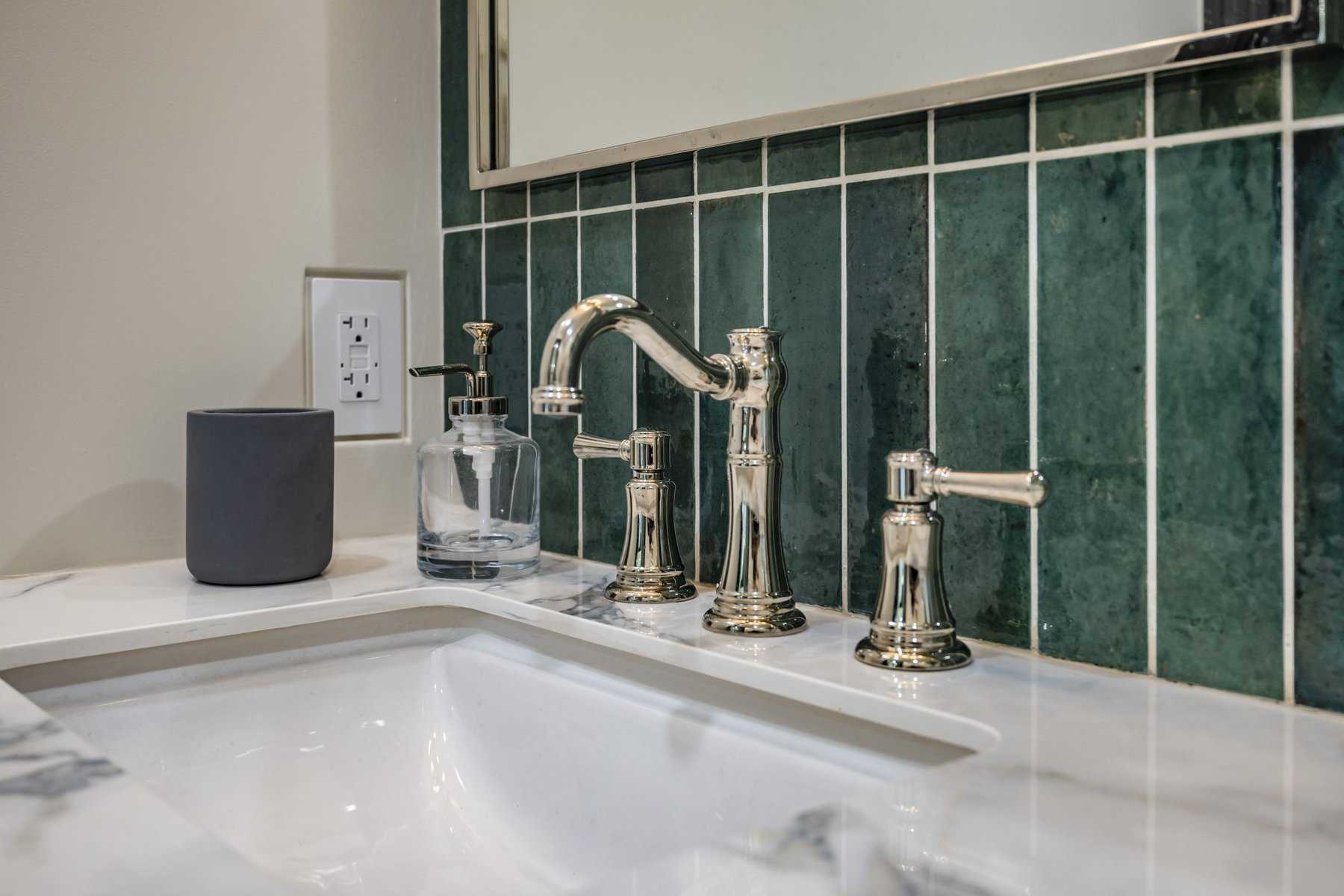 Bathroom sink with chrome faucet and green tile backsplash