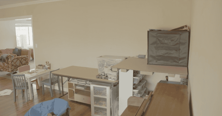 Cluttered home workspace with tables, bins, and kids’ furniture