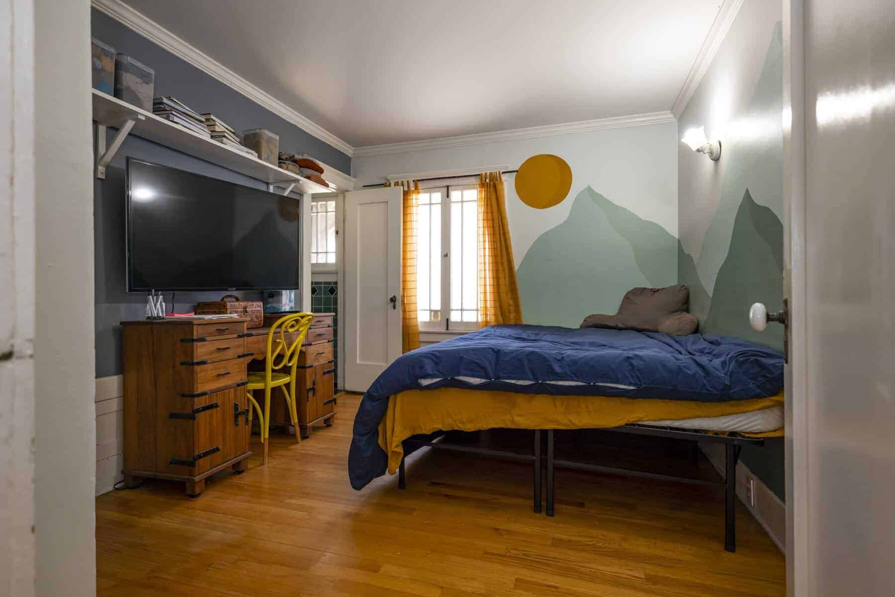 Cozy room with mountain mural, blue bedding, and desk setup