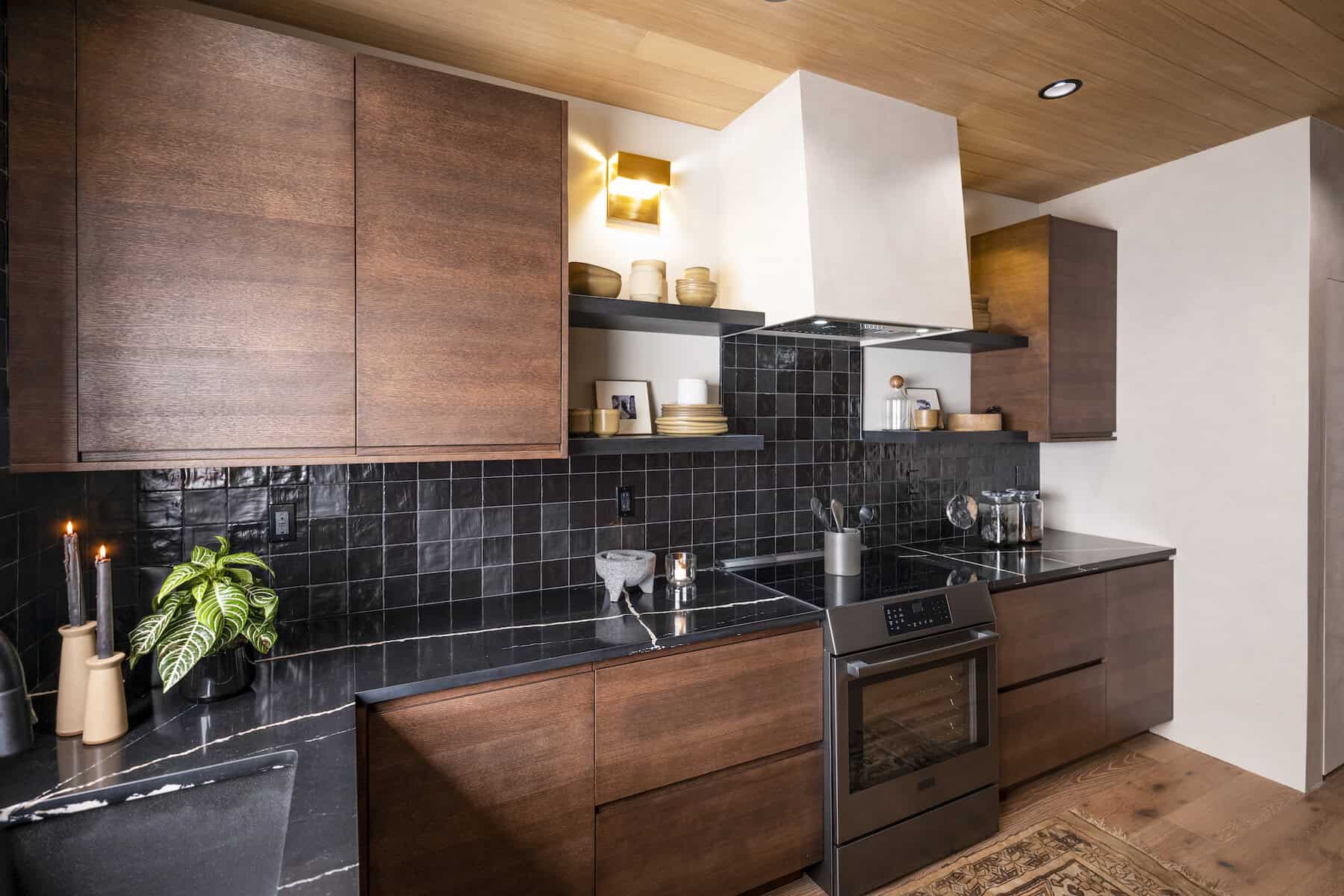 Contemporary kitchen with dark wood cabinetry, black tile backsplash, and modern appliances