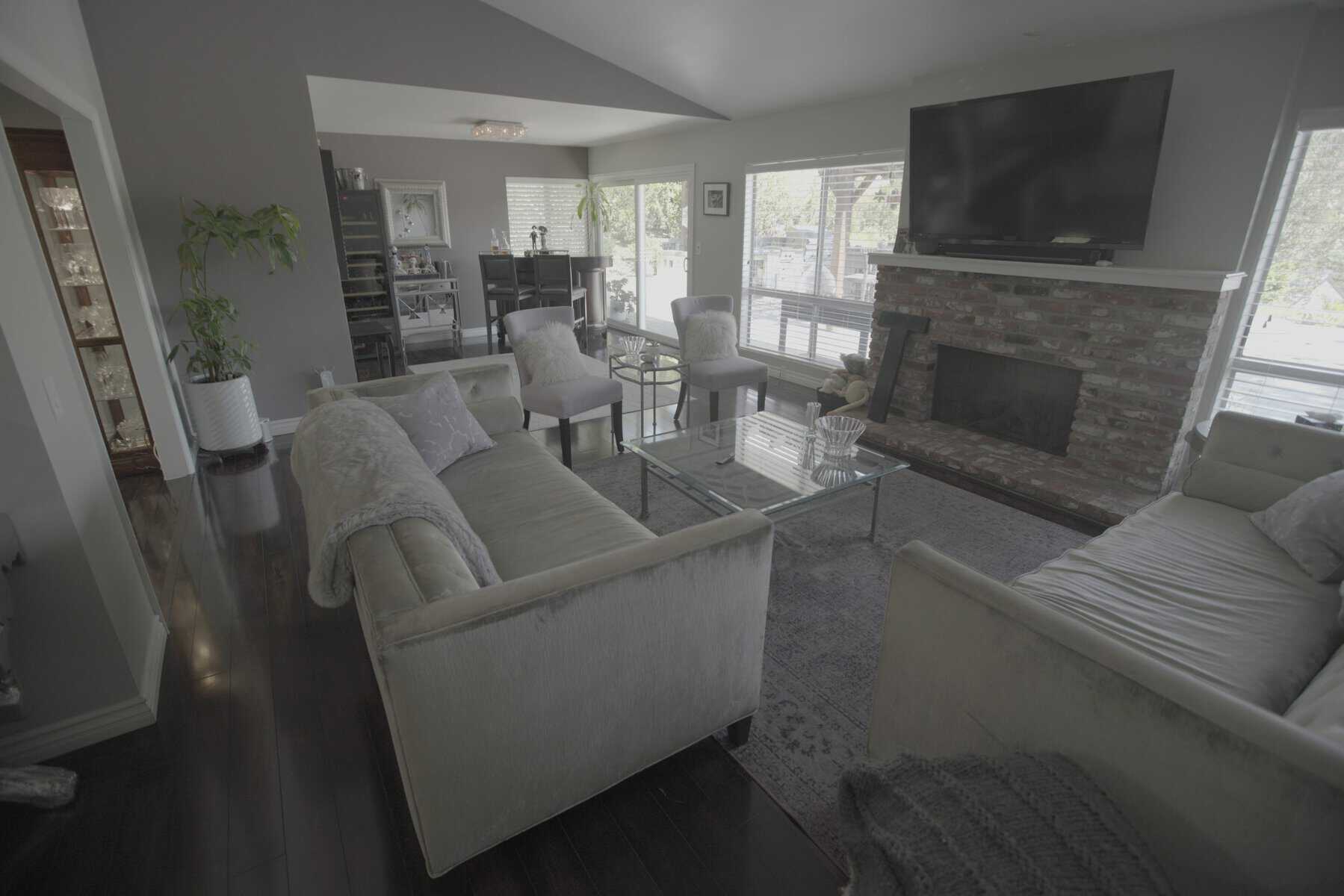 Spacious living room with velvet sofas, glass coffee table, brick fireplace, and large TV