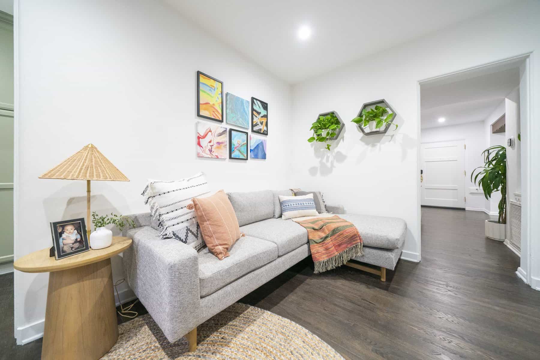 Cozy living room with gray sectional, wall art, hanging plants, and side table lamp