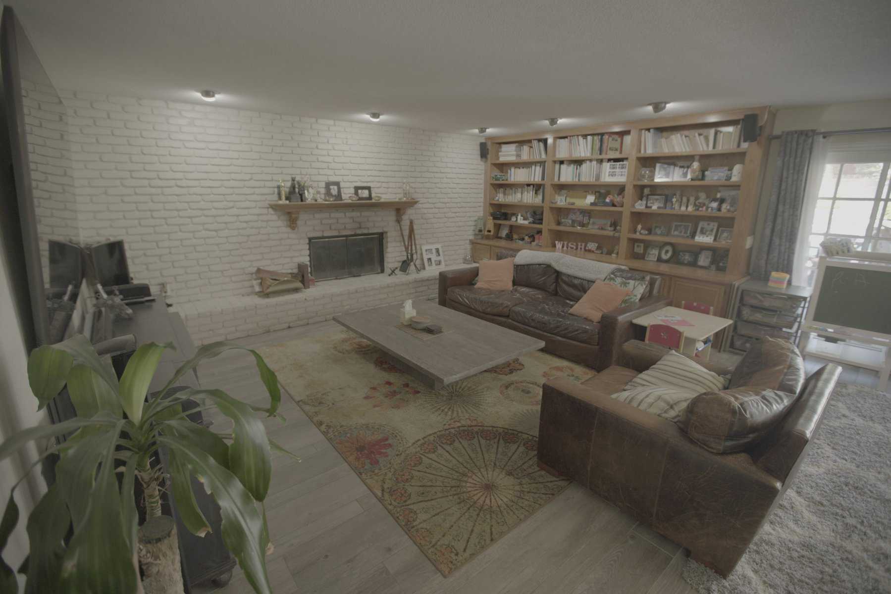 Living room with leather sofas, a brick fireplace, built-in bookshelves, and a patterned rug