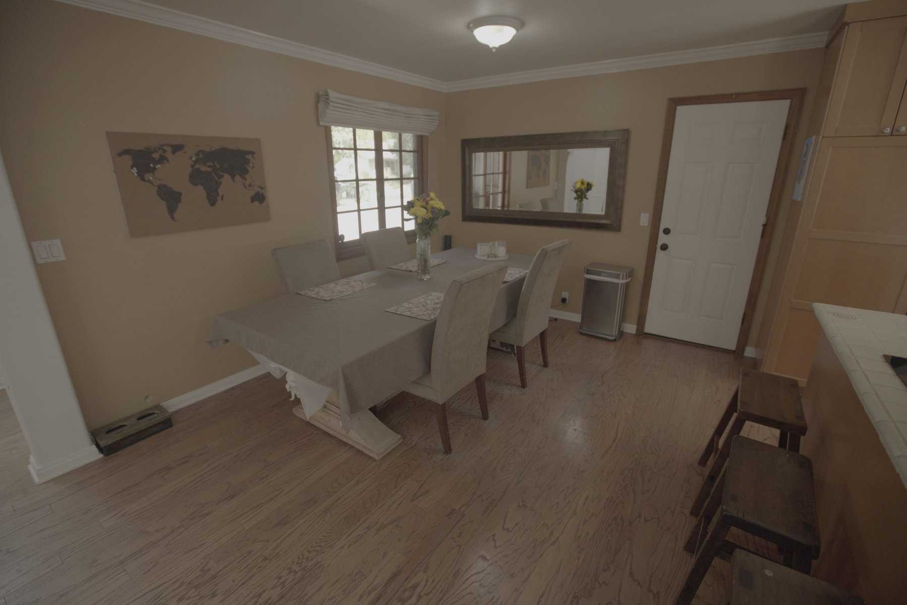 Simple dining room with beige walls, gray upholstered chairs, a large mirror, and a world map wall art