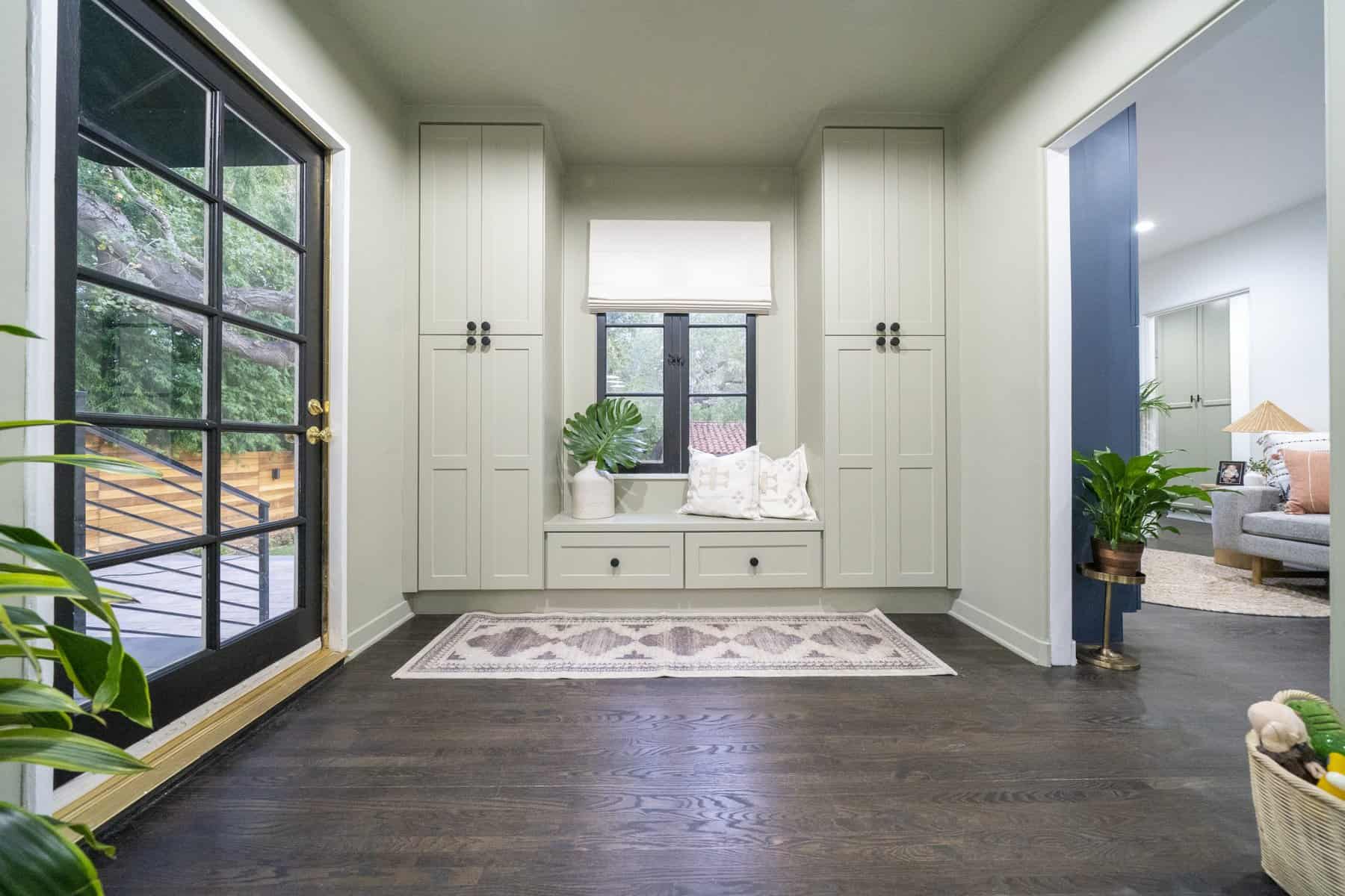 Mudroom with built-in cabinets, window bench, and dark wood floors