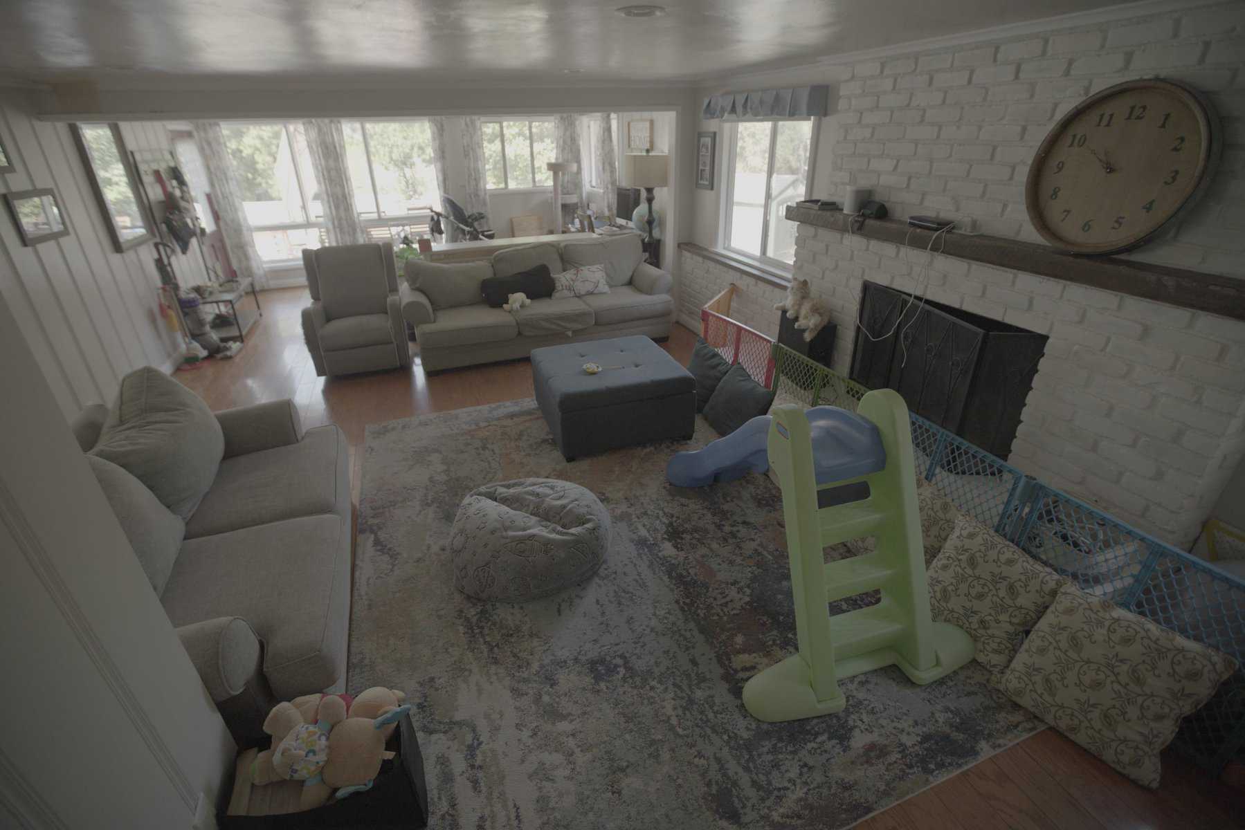 Living room with sofas, kids' play area, and white brick fireplace