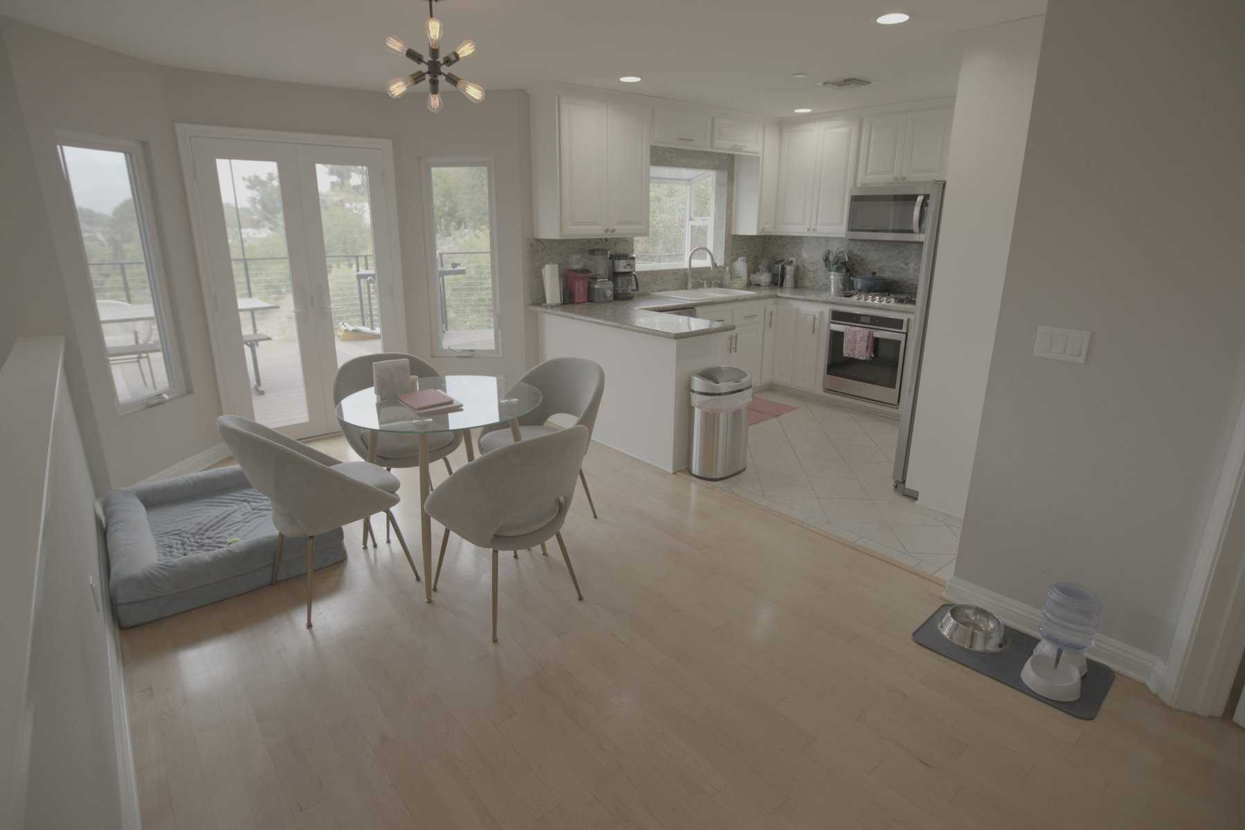 Modern kitchen and dining area with a glass table and dog bed
