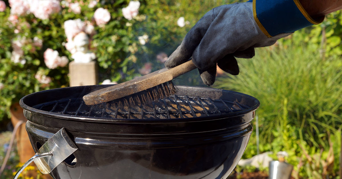 how to clean a barbecue grill man scraping grill with gloves on
