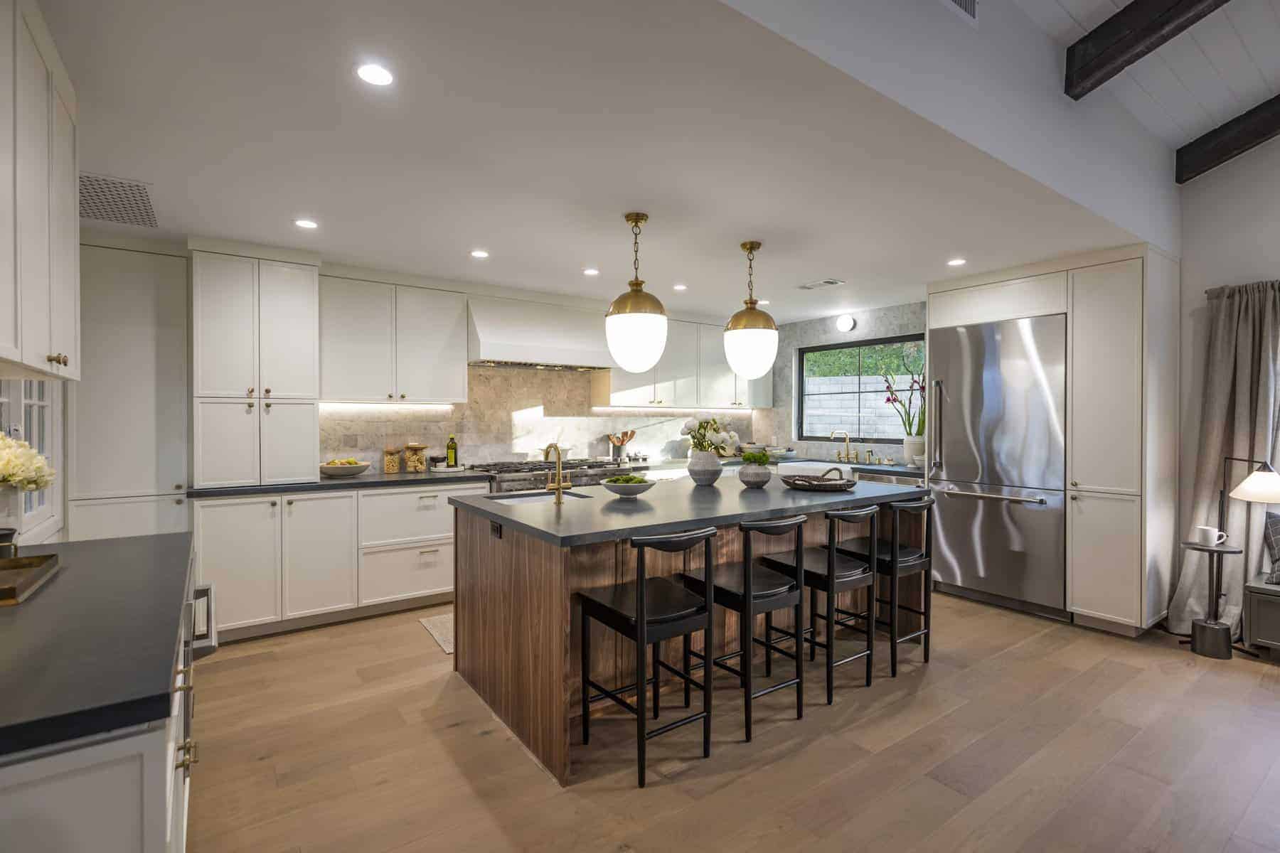Spacious kitchen with white cabinets, large island with dark countertop, and modern pendant lights