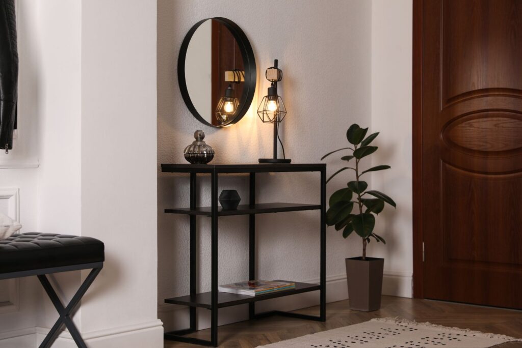 entryway with black console table, round wall mirror and floor plant