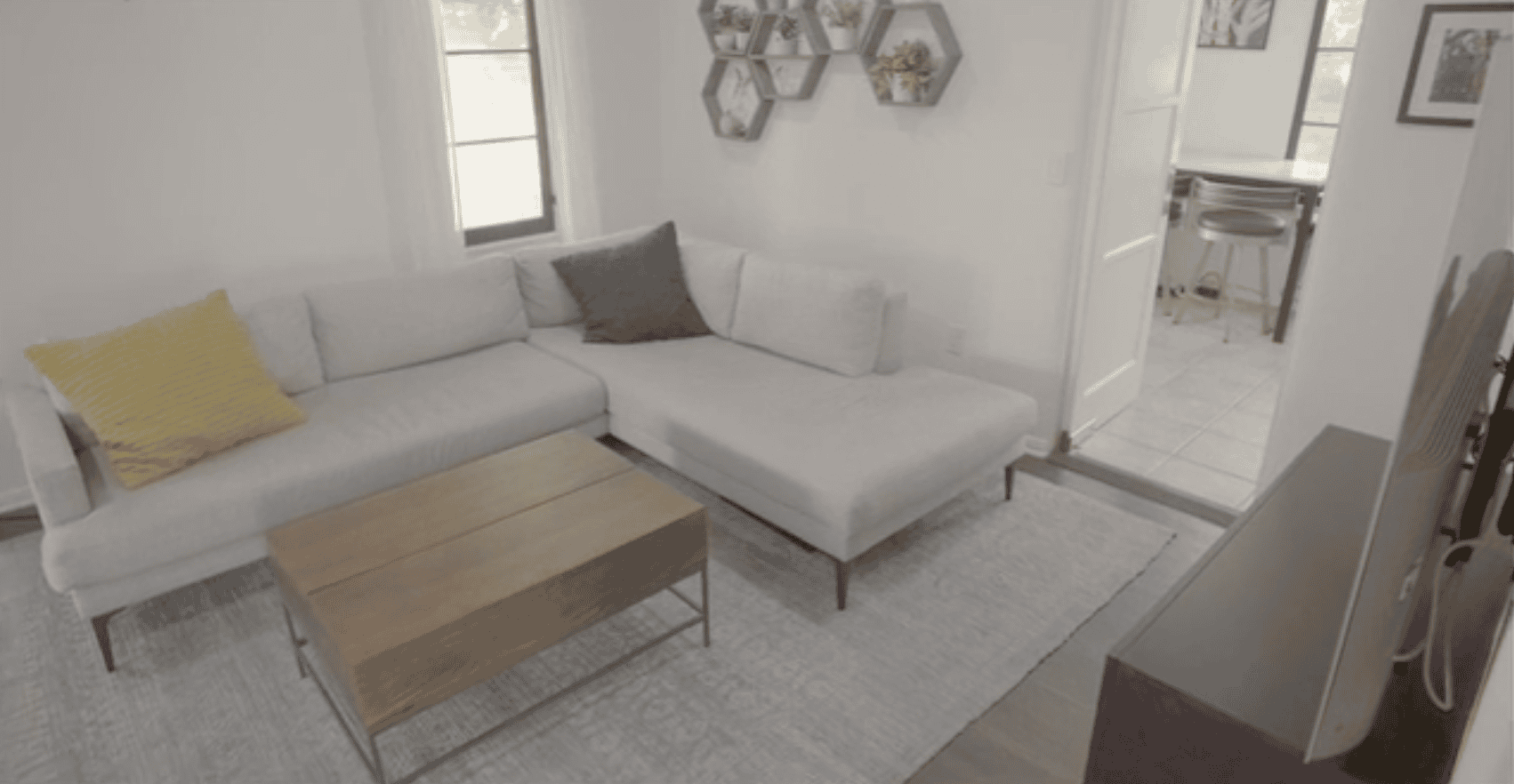 Living room with a gray sectional sofa, wooden coffee table, and hexagonal wall shelves