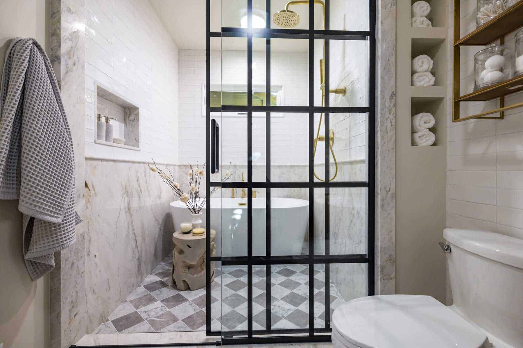 Modern bathroom with grid glass, gold fixtures, marble, and tub