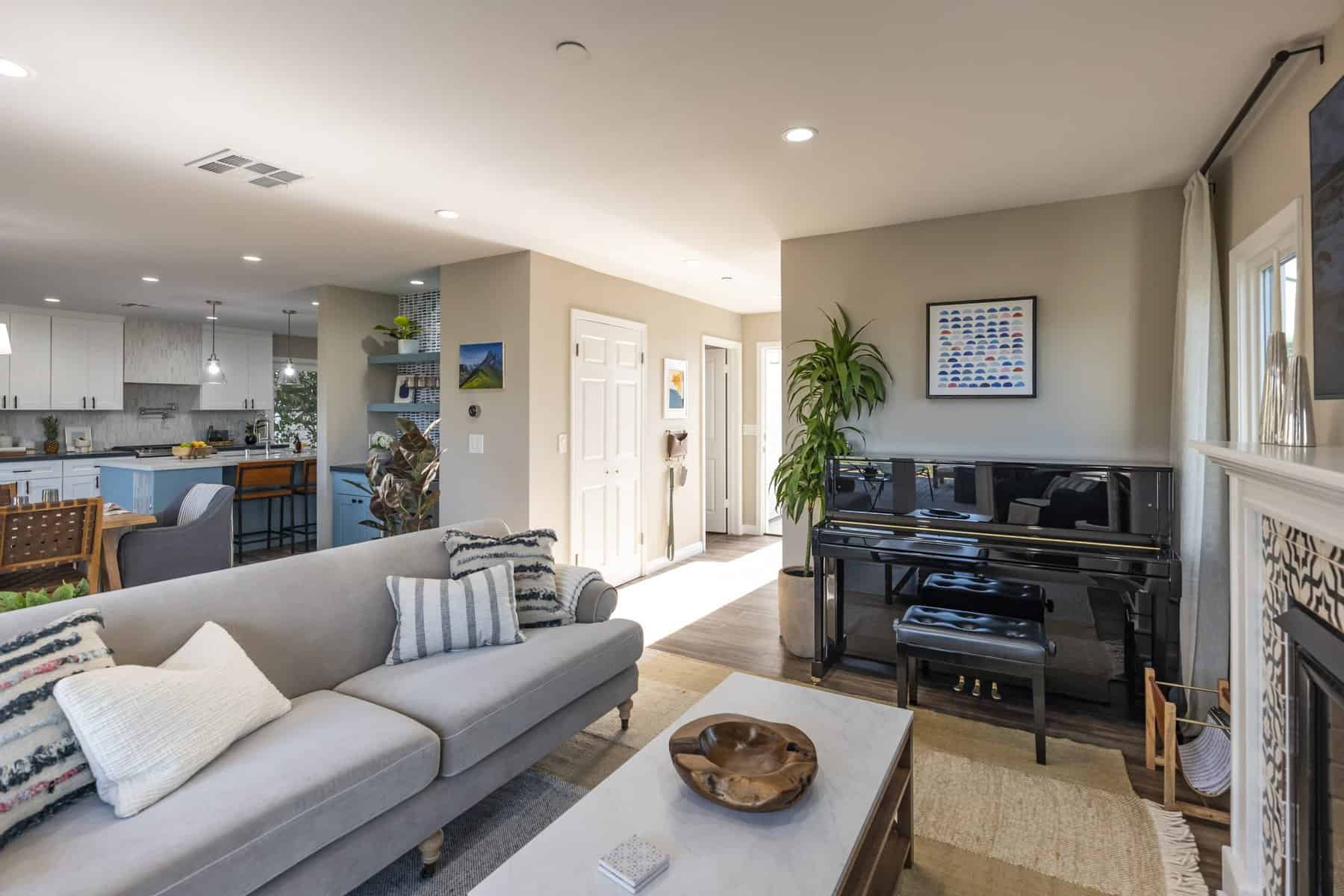 An open-plan living room with a gray sectional sofa, a coffee table, and a patterned rug