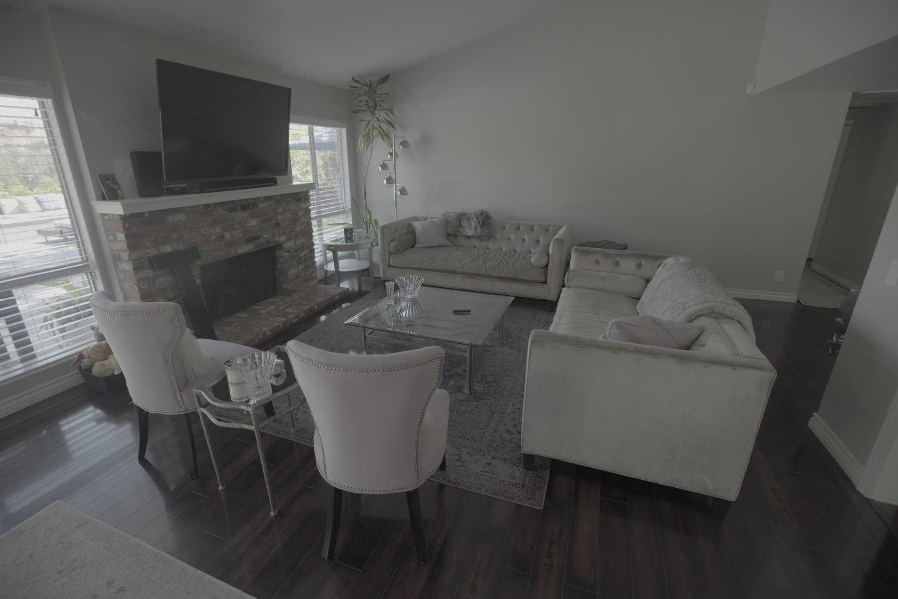 Living room with tufted sofas, brick fireplace, and glass coffee table