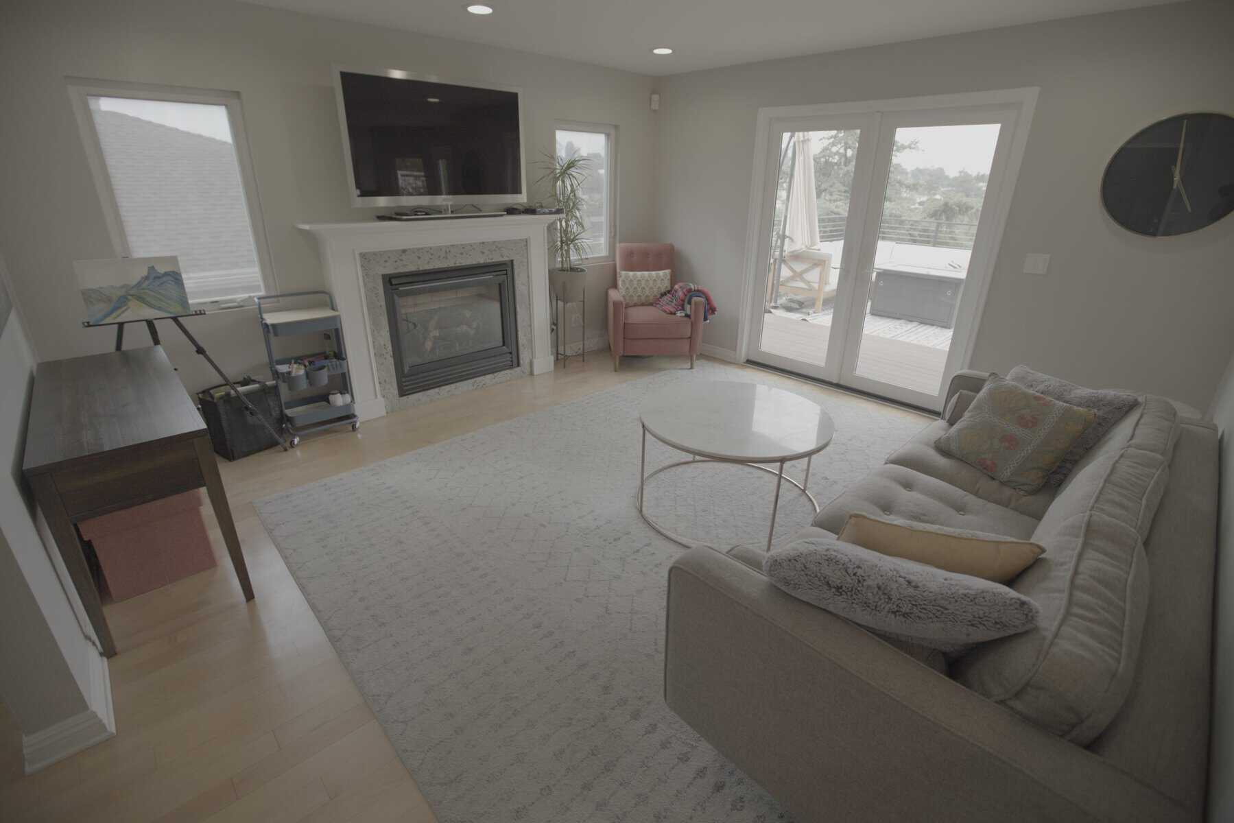 Bright living room with a fireplace, sofa, armchair, and large windows opening to a patio