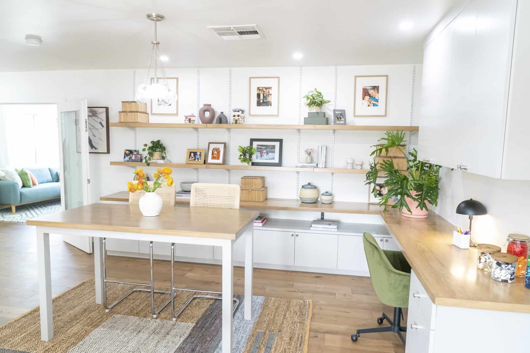 Bright home office with wood shelves, green chair, and table with orange flowers