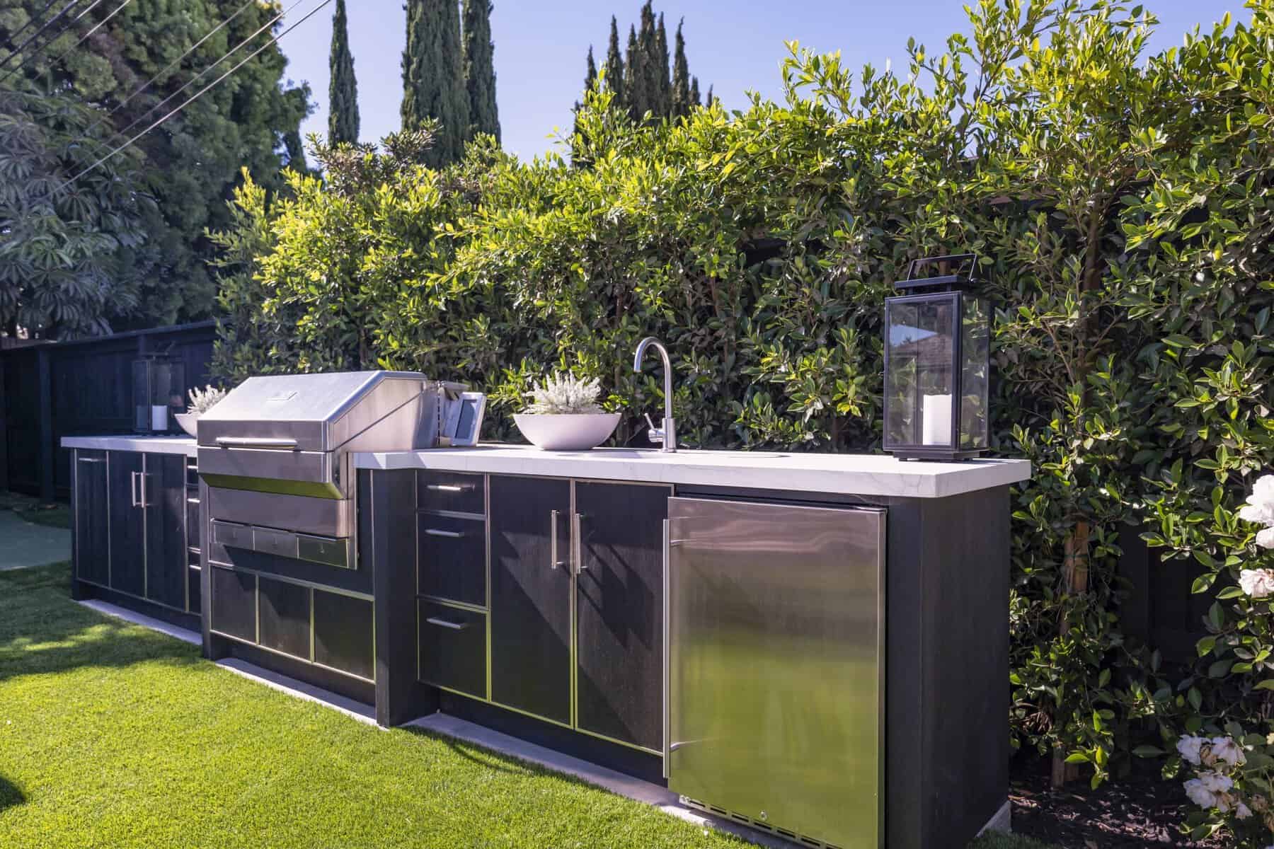 Modern outdoor kitchen with stainless steel grill, sink, and cabinets