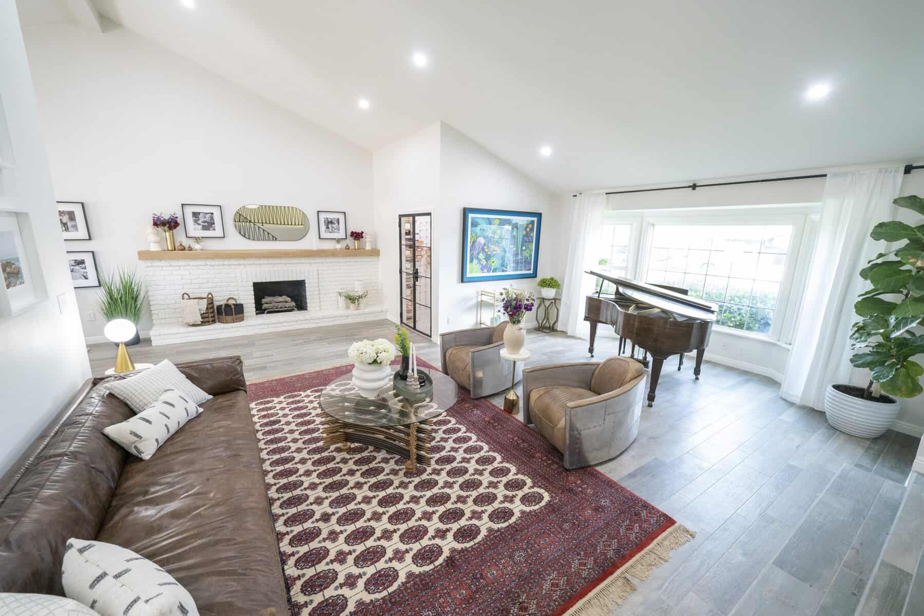 Bright living room with leather sofa, patterned rug, and grand piano
