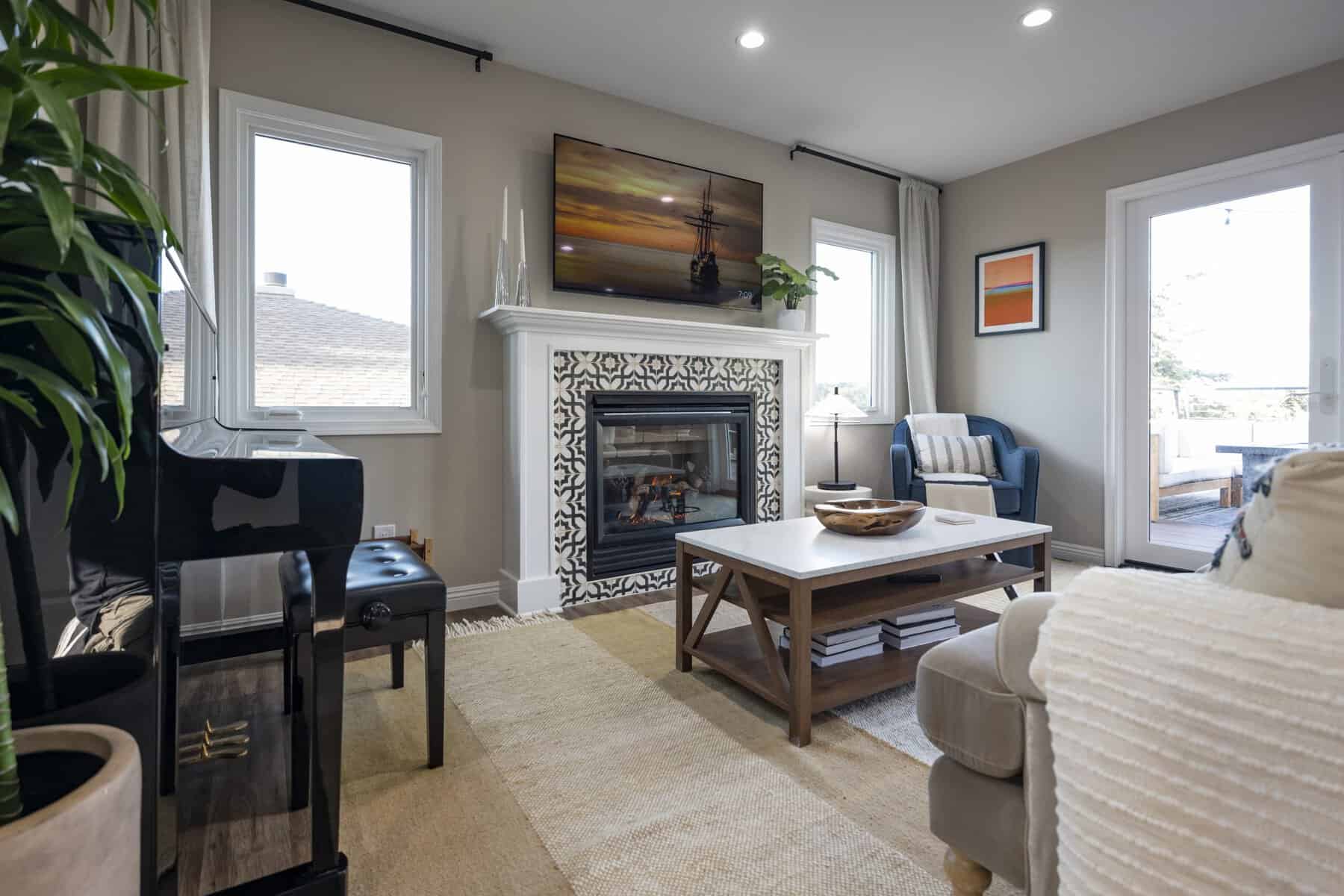 Cozy living room with a fireplace, piano, and seating by large windows and glass doors